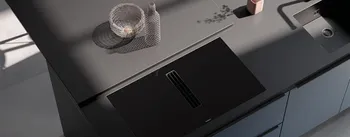 Edle schwarze Küche mit integrierter Spüle und Kochfeld. Design-Küchenarbeitsplatte mit klaren Linien, minimalistischer Gestaltung und stilvoller Dekoration in moderner Architekturbeleuchtung.